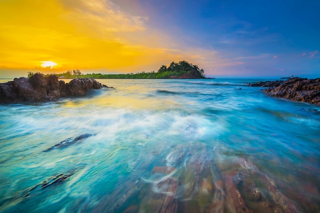 Lindo pôr do sol com pedras ao longo da praia