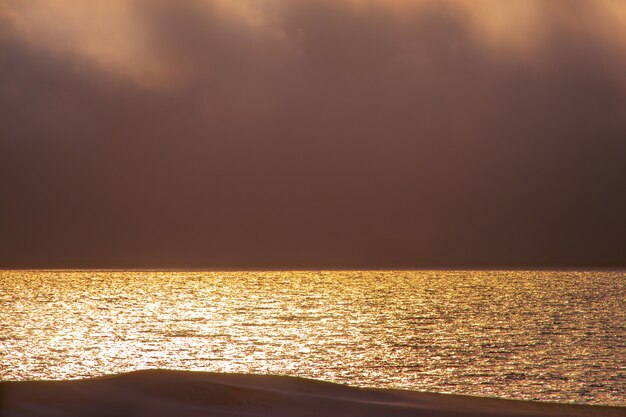 Lindo pôr do sol vermelho, nuvens escuras e oceano atlântico no horizonte