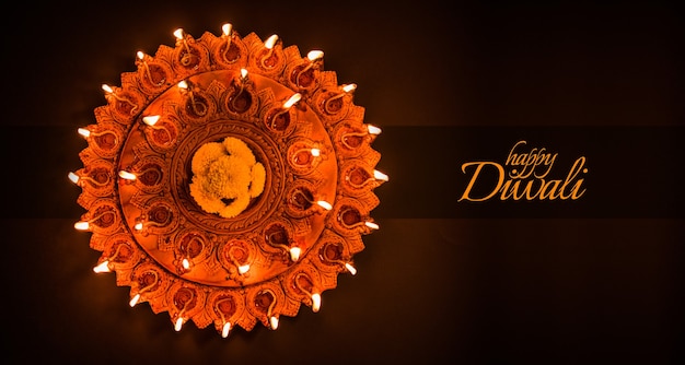 Lindo prato de terracota iluminado Diwali diya à noite, iluminação sombria, foco seletivo