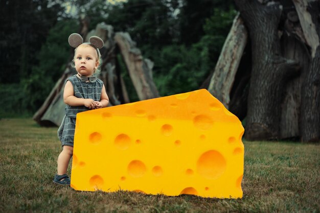 Un lindo ratoncito jugando con un gran trozo de queso en la hierba