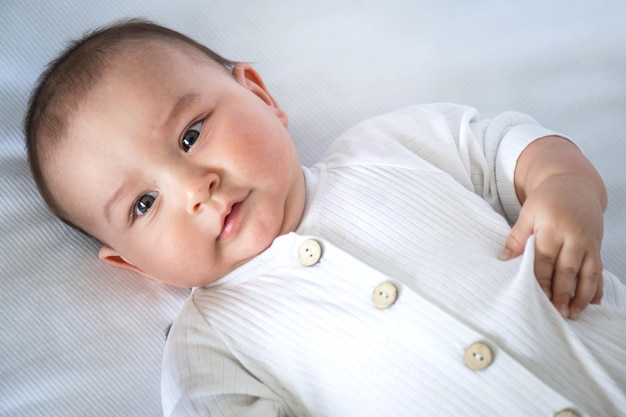 Lindo retrato de un bebé en un primer plano de cuna Un niño vestido de blanco en ropa interior blanca Ternura y cuidado de los problemas de los niños