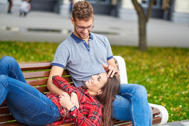 Lindo retrato de um jovem casal eles estão sentados no banco abraçando e beijando