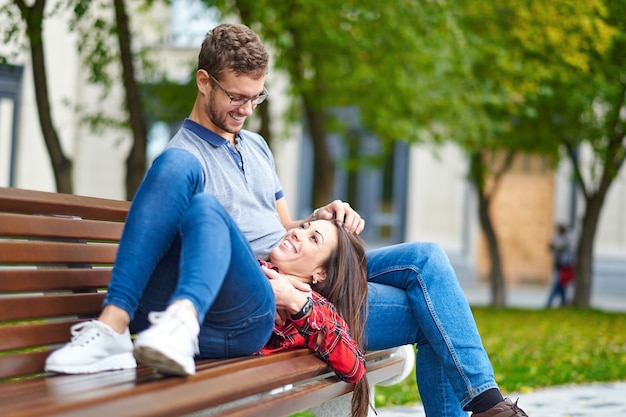 Lindo retrato de um jovem casal. Eles estão sentados no banco, se abraçando e se beijando.