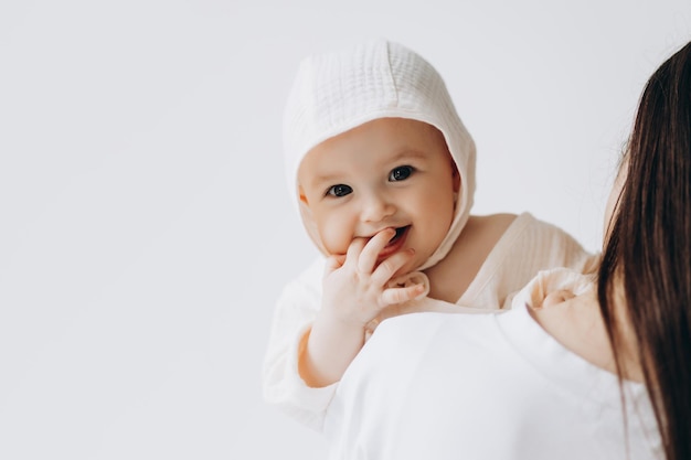 Lindo retrato de estudio de una niña recién nacida posando para una foto en los brazos de su madre