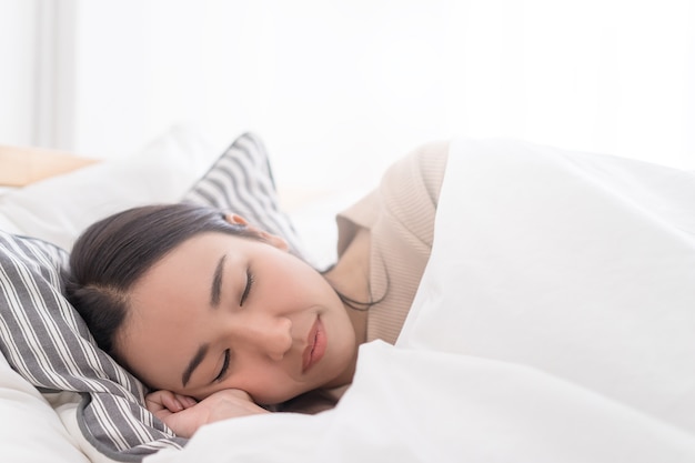 Lindo retrato femenino asiático de dormir en una cama de la mañana