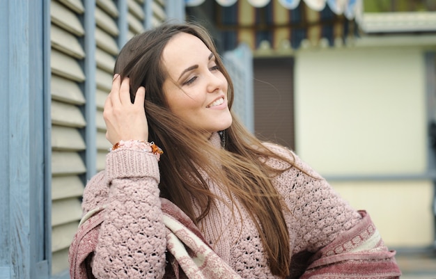 Lindo retrato de mujer joven vestida con un suéter suave y aretes de estilo boho rosa hechos a mano, moda al aire libre de otoño