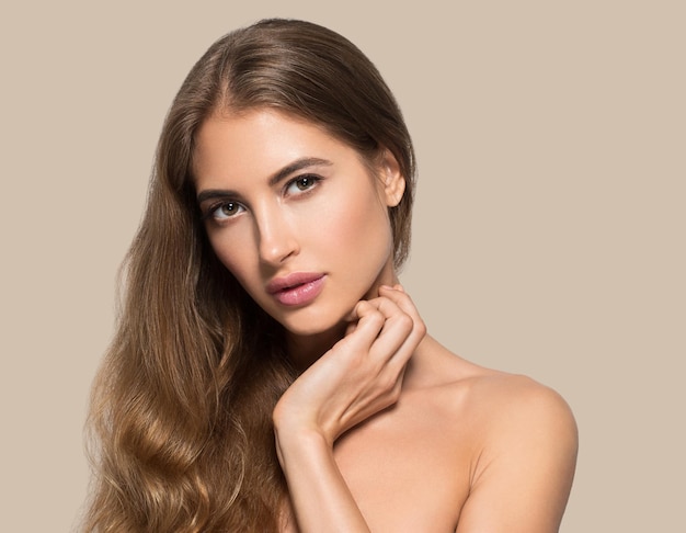 Lindo rosto de mulher saudável. Jovem modelo de beleza se tocando. Cor de fundo. marrom