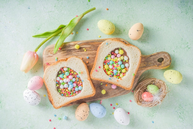 Lindo sándwich de desayuno dulce. Idea creativa para merienda o almuerzo de Pascua. Sándwich tostado con mantequilla de maní y pasta de chocolate, con vista superior de chispitas de azúcar de colores.