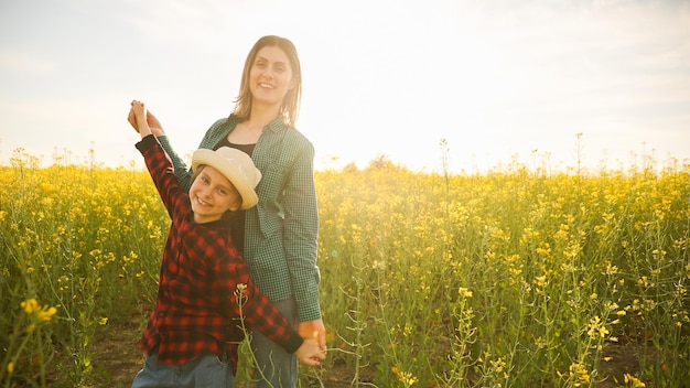 Lindo sonriente caucásico granjero familia madre e hijo de pie en un niño feliz de colza floreciente y