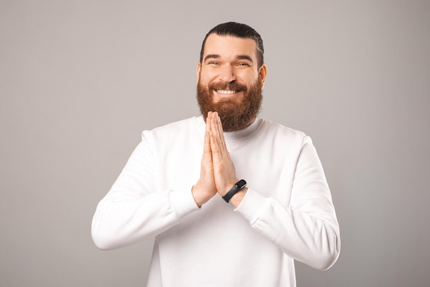 Lindo sonriente joven barbudo está tomados de la mano juntos para la oración