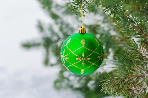 lindo verde com enfeite de ouro bugiganga de natal pendurada em um galho de abeto