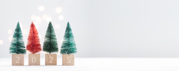 Lindos abetos en miniatura de Navidad en una mesa blanca con luces bokeh