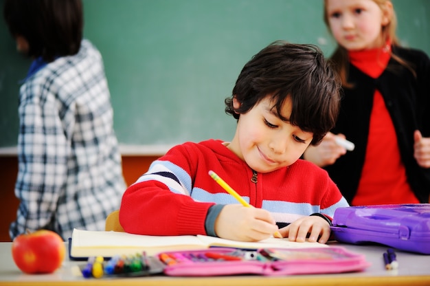 Lindos adorables escolares en el aula con actividades educativas