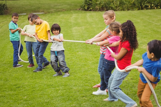 Lindos alumnos jugando tira y afloja en el césped fuera