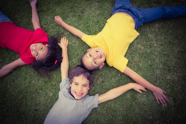 Lindos alumnos tumbados en la hierba sonriendo