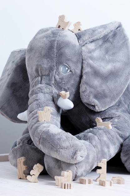 Lindos animales de juguete de madera en un tablón de madera blanca con una muñeca elefante gigante en el fondo pequeños juguetes y poca profundidad de campo