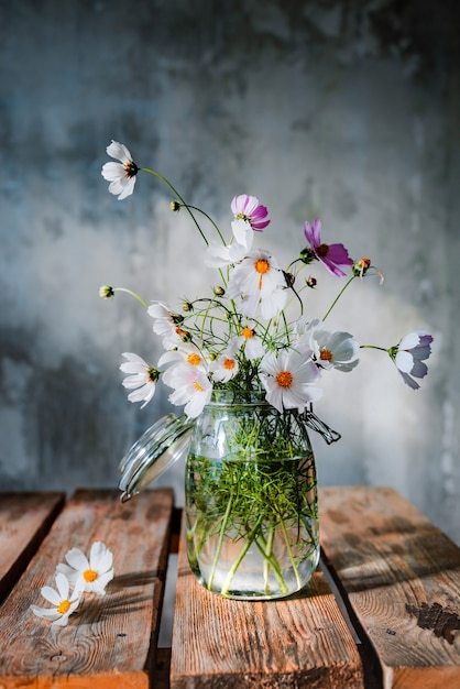 Lindos buquês de flores silvestres em uma mesa de madeira em uma parede de concreto frio