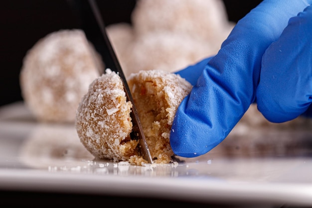 Lindos doces com coco são cortados com uma faca em um prato branco sobre fundo preto