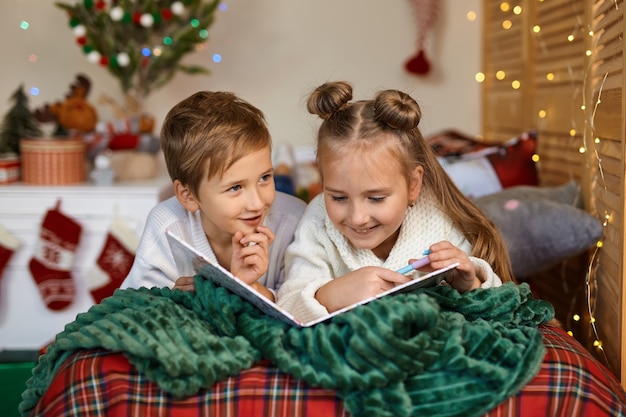 Lindos dos niños felices escribiendo una carta a Santa