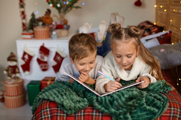 Lindos dos niños felices escribiendo una carta a Santa