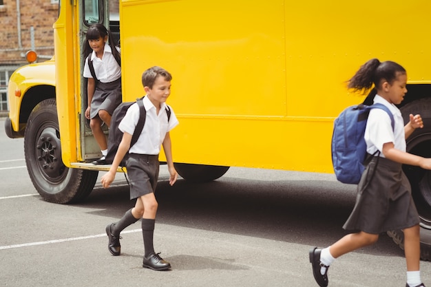 Foto lindos escolares que bajan del autobús escolar