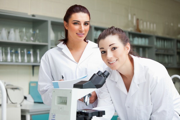 Lindos estudiantes de ciencias posando con un microscopio