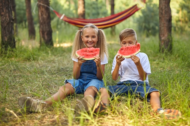 Foto lindos filhos comendo melancia no jardim.