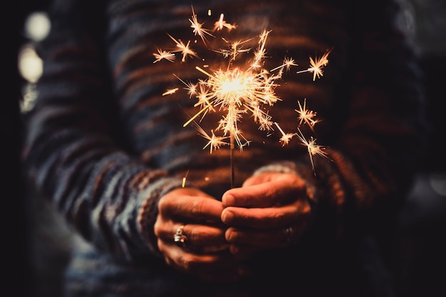 Lindos fogos de artifício de luz cintilante segurados por mãos de adultos