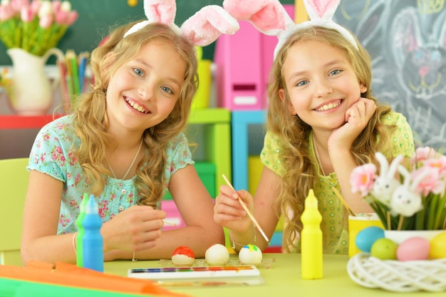 Lindos gemelos con orejas de conejo decorando huevos de Pascua