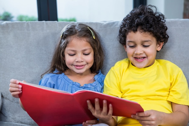 Foto lindos irmãos lendo um livro no sofá