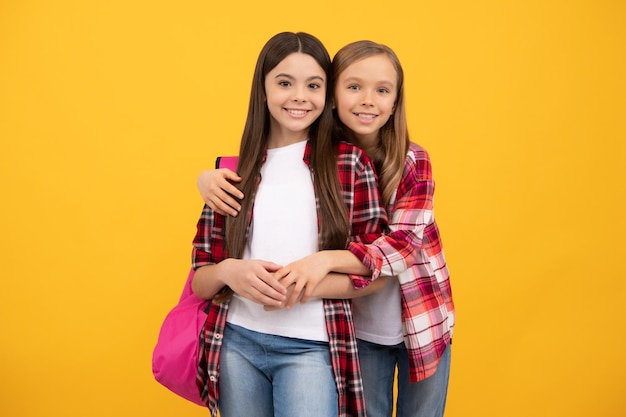 Lindos niños abrazados en camisa casual a cuadros llevan mochila, universidad.