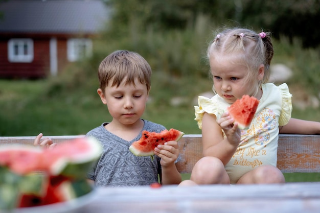 Lindos niños caucásicos comiendo sandía en el campo