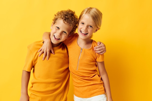 Lindos niños en edad preescolar en camisetas amarillas de pie lado a lado emociones infantiles fondo amarillo inalterado