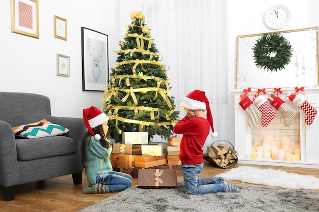 Lindos niños con gorro de Papá Noel con regalo de Navidad en casa