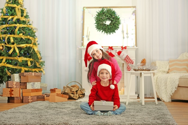 Lindos niños con gorro de Papá Noel con regalo de Navidad en casa