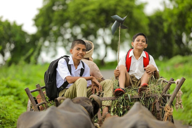 Lindos niños indios con mochila en el carro de bueyes