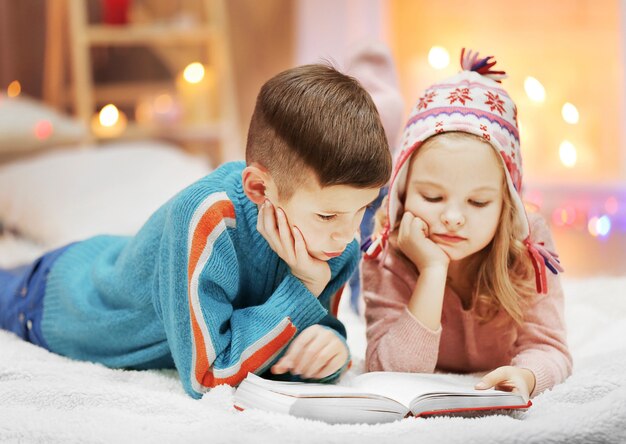 Lindos niños leen libros en el suelo de la habitación decorada