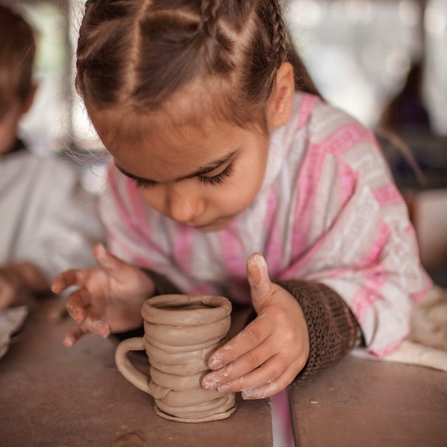 Lindos niños pequeños jugando junto con plastilina en el taller de cerámica, artesanía y arte de arcilla