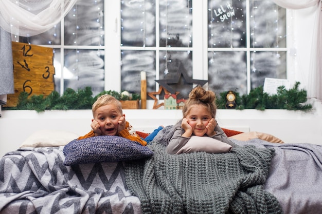 Lindos niños pequeños niño y niña en casa esperando a Santa Claus