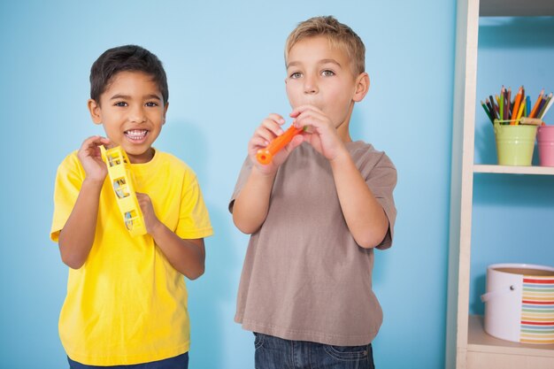 Lindos niños pequeños tocando instrumentos musicales en el aula