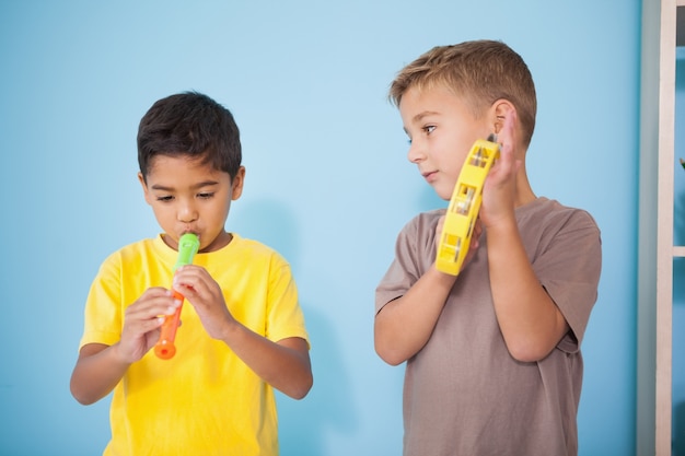 Lindos niños pequeños tocando instrumentos musicales en el aula