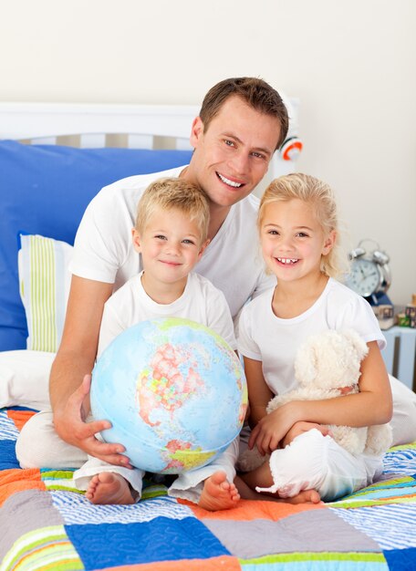 Lindos niños y su padre mirando un globo terrestre