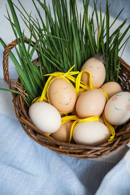 Lindos ovos de páscoa pintados com um rosto bonito que se encontram em uma cesta de madeira junto com grama verde cartão postal de páscoa