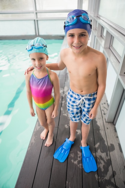 Lindos pequeños hermanos de pie junto a la piscina