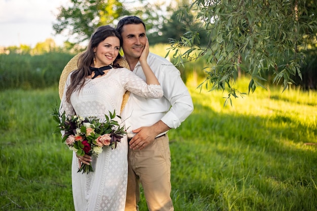Lindos recién casados abrazándose y sonriendo en un parque verde Retrato de la novia y el novio en un vestido de encaje
