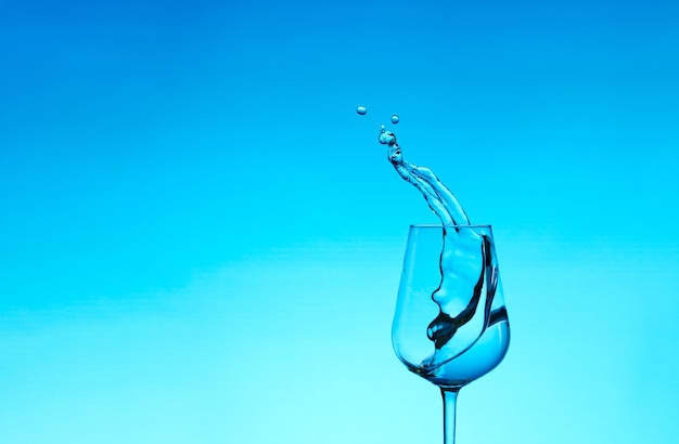 Lindos salpicos de água em uma taça de vinho, com filtro azul, fechem com espaço de cópia.