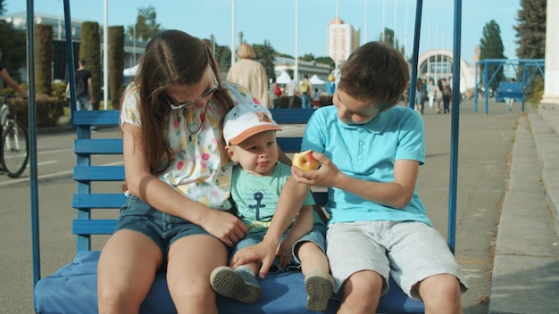 Foto lindos tres hermanos montando en columpio al aire libre niños adorables pasando tiempo en el parque