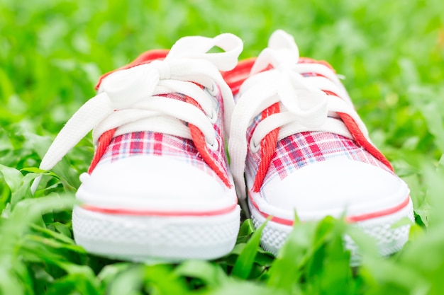 Lindos zapatos de bebé rojo y blanco sobre hierba verde