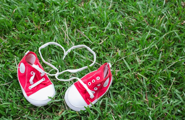 Lindos zapatos de lona pequeños rojos en la hierba