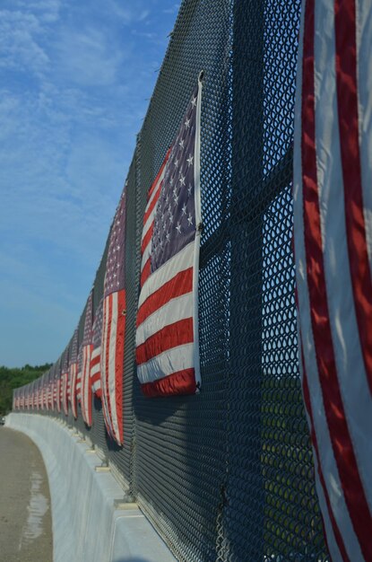 Foto línea de banderas estadounidenses en la valla del paso elevado de la autopista en el lado soleado de la carretera